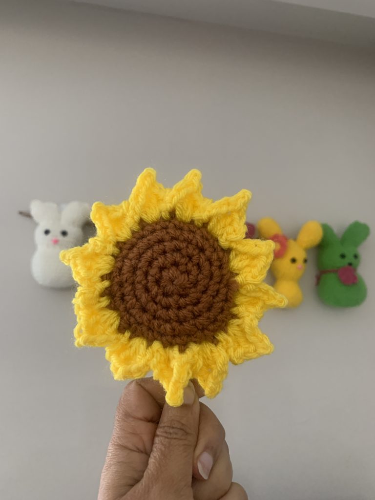 A hand holding a big crocheted sunflower